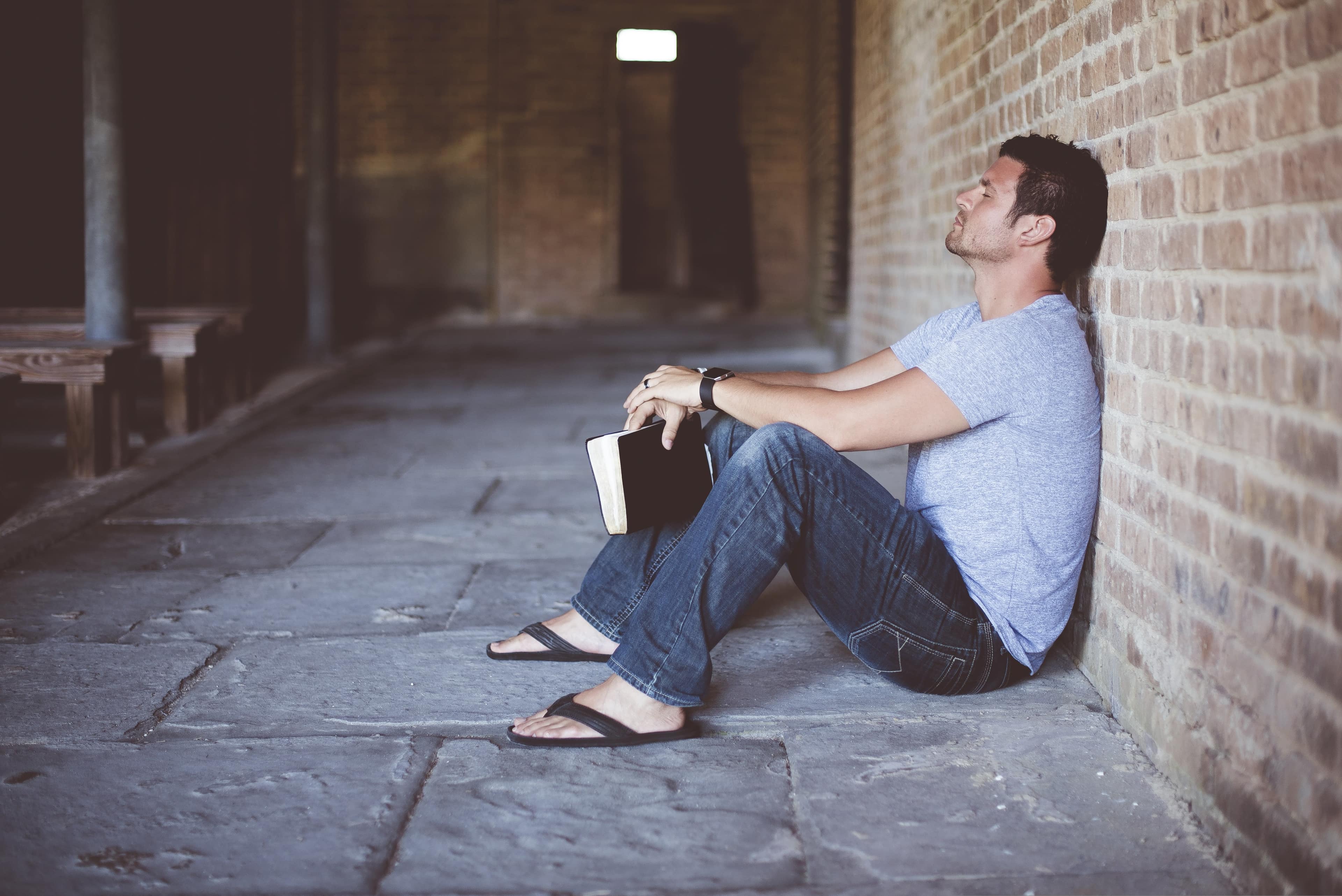 A person sitting with an open Bible, searching for answers in quiet reflection