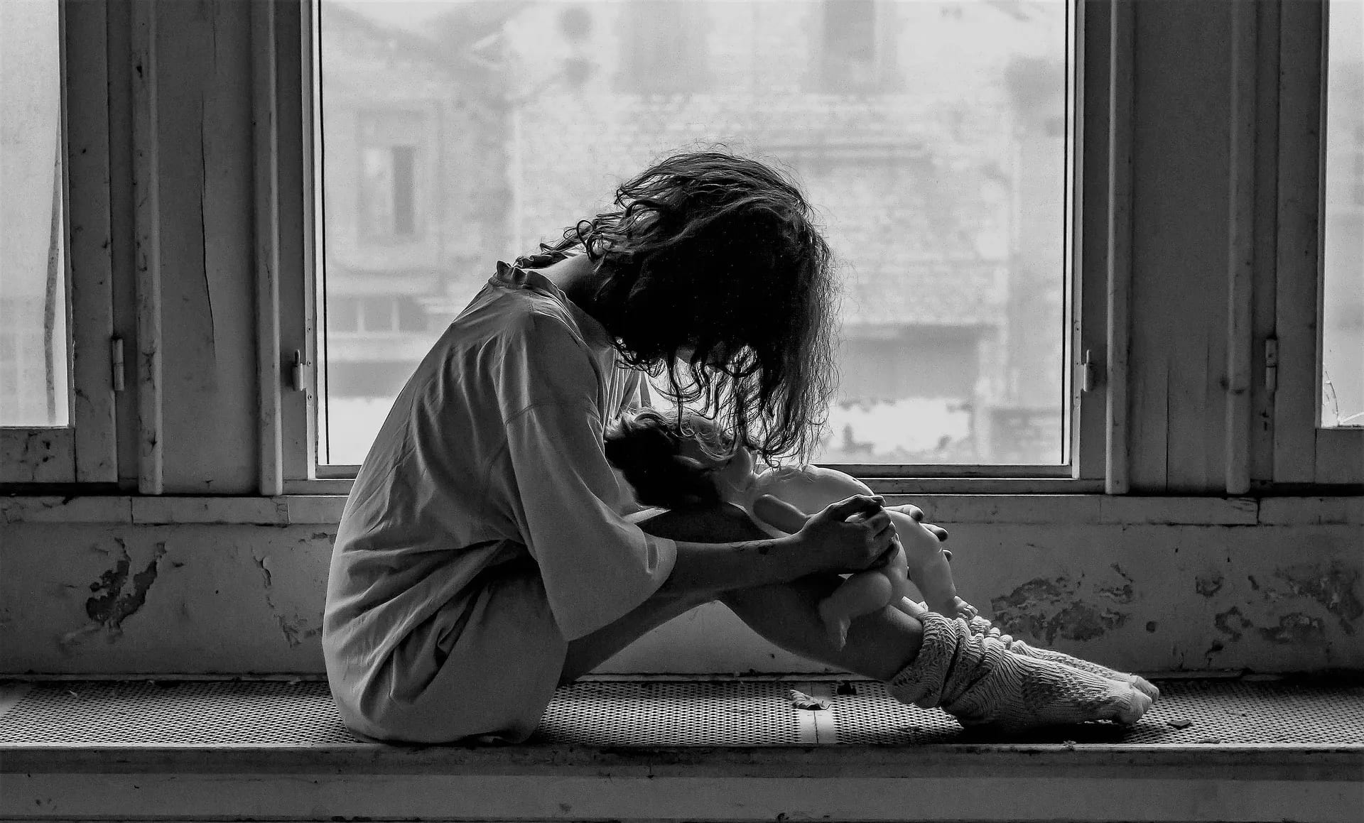 A young person sitting alone by a window at night, reflecting the loneliness and anxiety experienced by Gen Z
