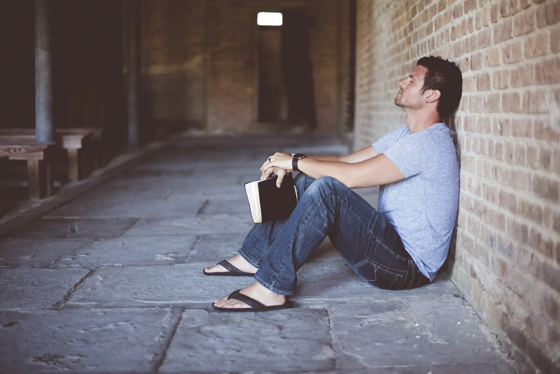 A person sitting with an open Bible, searching for answers in quiet reflection